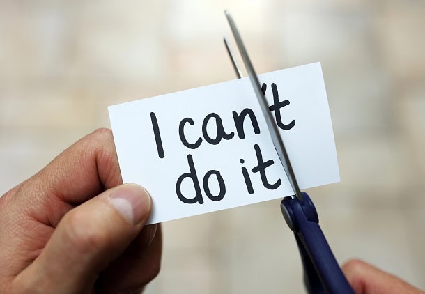 Hands using a scissor to cut away the T in I can