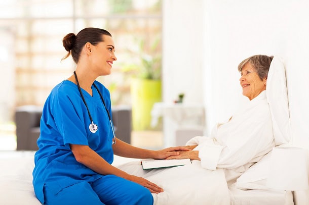 A nurse talking to a patient who is in a hospital bed.