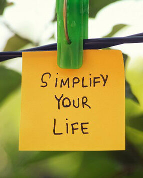 A post-it note hanging on a tree that says: Simplify Your Life.