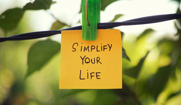 A post-it note hanging on a tree that says: Simplify Your Life.