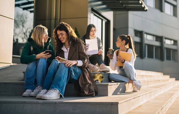 Girls having fun while sitting on the stairs leading to the school.
