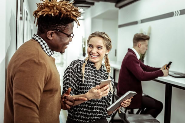 Colleagues smiling at something on a smart phone in an office setting.
