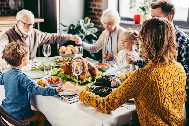 A family saying a prayer before Thanksgiving dinner.