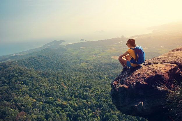 A woman looking at the view from the top of a mountain.