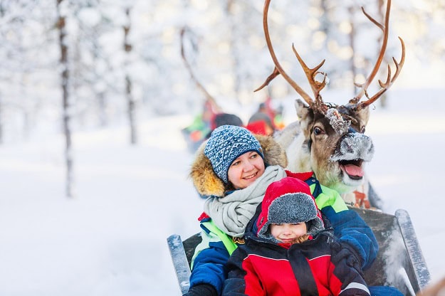 A mom and her kids at a reindeer safari in winter.