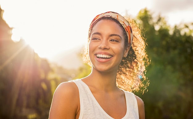 A smiling woman out in the sunshine.