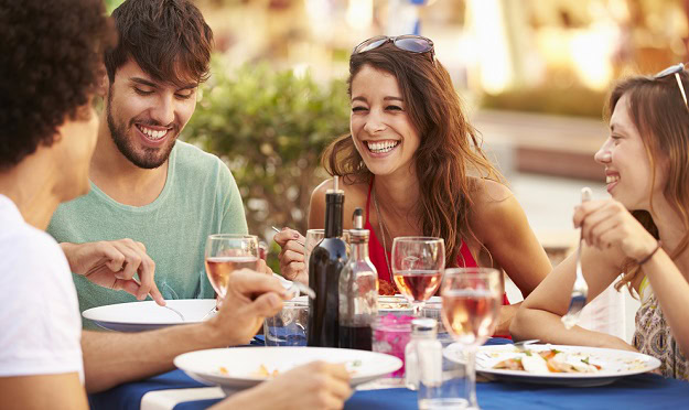 Happy friends enjoying a meal while sitting outside.