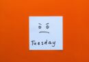 A somewhat irritated or angry smiley on a post-it note with the word Tuesday written below it.