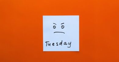 A somewhat irritated or angry smiley on a post-it note with the word Tuesday written below it.