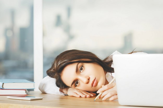 A woman in an office looking unmotivated and tired.