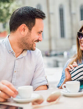A happy couple sitting outside and having coffee.