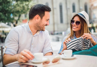 A happy couple sitting outside and having coffee.