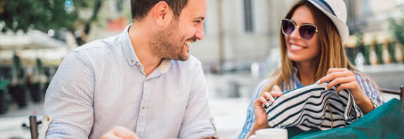 A happy couple sitting outside and having coffee.
