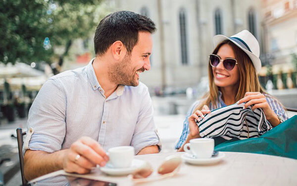 A happy couple sitting outside and having coffee.