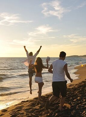 Friends running on the beach during a summer sunset.