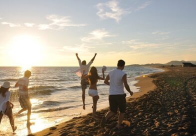 Friends running on the beach during a summer sunset.