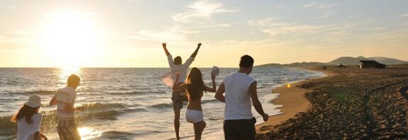 Friends running on the beach during a summer sunset.