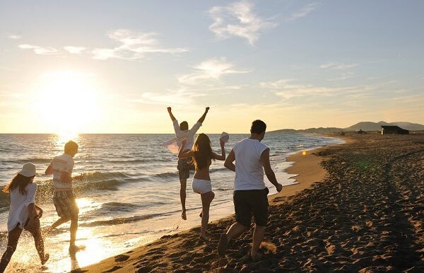 Friends running on the beach during a summer sunset.