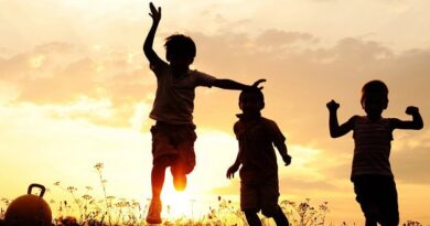 Happy kids running in the grass at sunset.