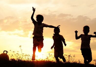 Happy kids running in the grass at sunset.
