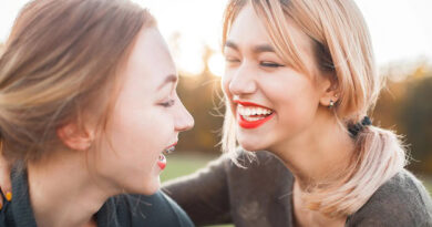 Two women laughing outdoors in the sun.
