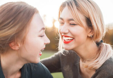 Two women laughing outdoors in the sun.