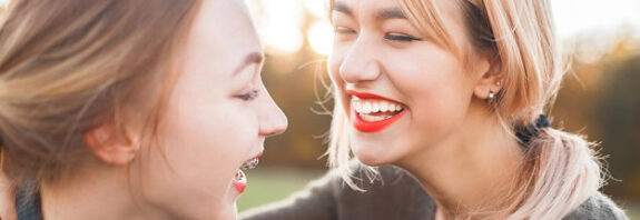 Two women laughing outdoors in the sun.