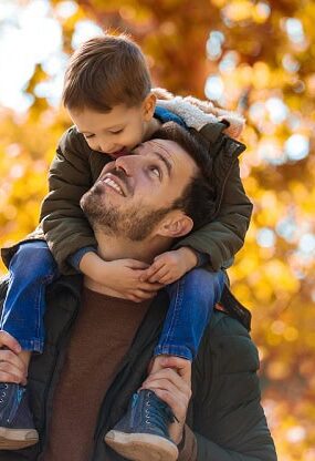 A smiling son riding on his father