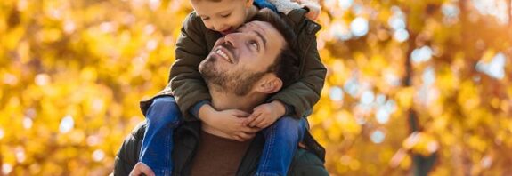 A smiling son riding on his father