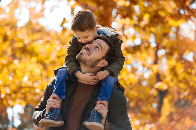 A smiling son riding on his father