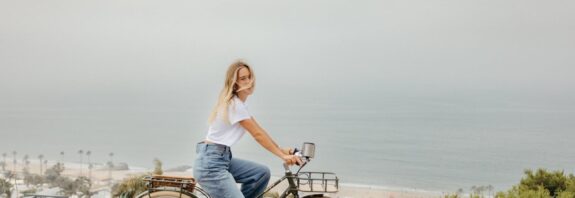 Woman biking by the ocean.