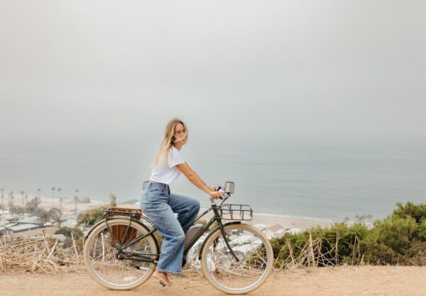 Woman biking by the ocean.
